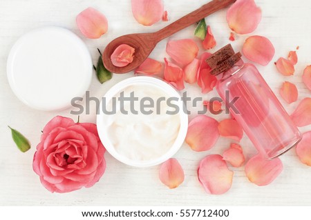 Skincare beauty treatment plant-based products with pink rose petals. Jar of body moisturizer, attar bottle toning lotion, top view homemade cosmetic ingredients