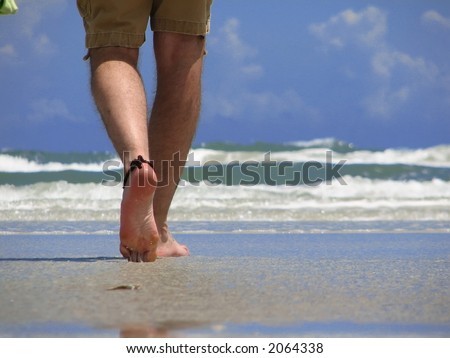 Closeup of a man\'s leg walking on new smyrna beach, florida.