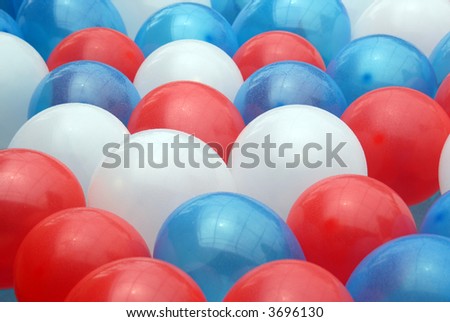 Shot of several balloons, red, blue, and white floating in a pool.  The balloons were used as decoration on 4th of July.