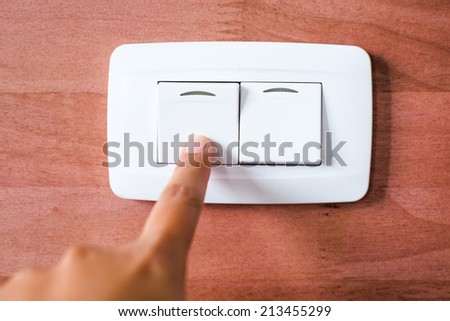 Turning off  on wooden wall-mounted light switch - energy saving concept