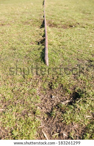 old and rusty natural gas pipe enters on the ground among the green grass. Selective focus