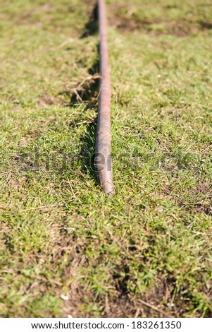 old and rusty natural gas pipe enters on the ground among the green grass. Selective focus