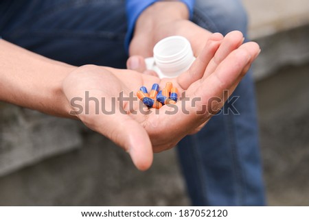 Depressed teenage boy with many tablets in hand, wants to take an overdose. concept of loneliness, misunderstanding, lack of integration