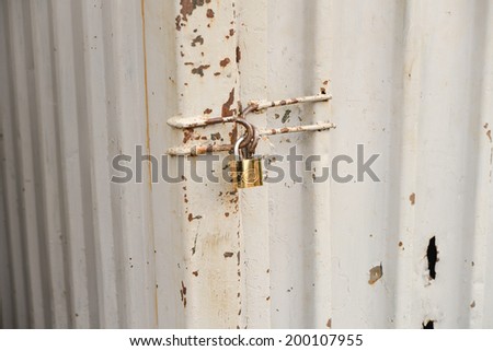 close up of a rusty steel door securely locked with a golden padlock