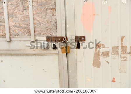 close up of a rusty steel door securely locked with a golden padlock