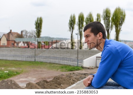 Unhappy teenage student sitting outside on stadium steps