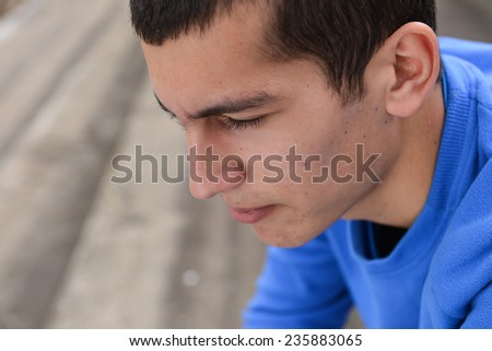 Close up of an unhappy teenage student sitting outside on stadium steps