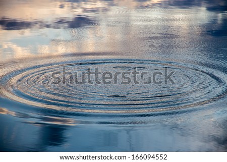 Circles on the water of a lake and sky reflection