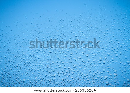 rain drops on a window as pure blue background