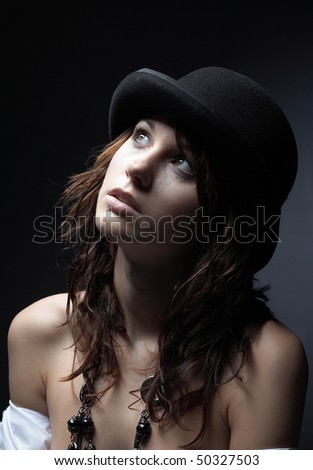 Beautiful young woman wearing black hat on black background - crying girl