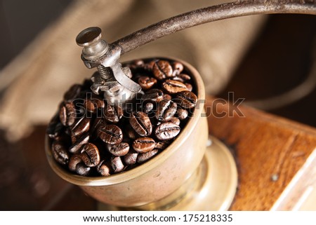 Overhead view of a vintage coffee grinder with coffee beans and burlap coffee bag