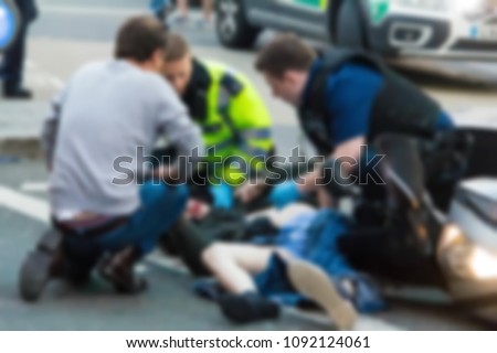 The paramedics and firemen provide first aid to victims in a motorcycle accident on Piccadilly Street. Blurred view