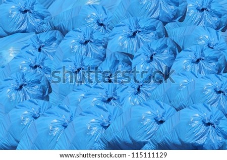 A pile of blue garbage bags with tons of trash