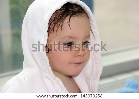 Little girl (one year and six months of age) in a white robe after a swimming pool