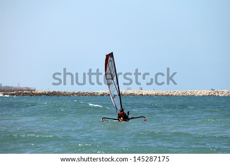 Small trimaran with sail preparing to go to sea in the hot summer day on the beach