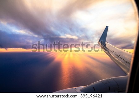 Wing  of big airplane on beautiful orange sunset background, fast aerial transport, traveling and voyage concept. Looking Out Through Airplane Window