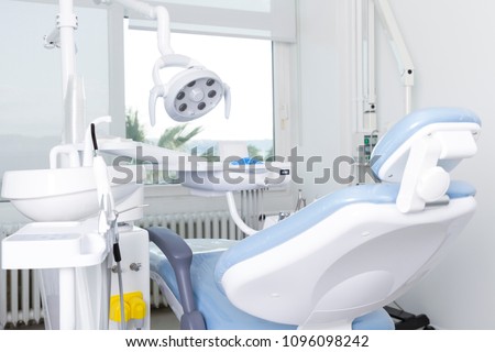 Modern Dental Clinic, Dentist chair and other accessories used by dentists in blue medical light. Dental surgeon, is a surgeon who specializes in dentistry and treatment of conditions of oral cavity.