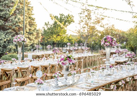 Wedding. Banquet. Chairs and honeymooners table decorated with candles, served with cutlery and crockery and covered with a tablecloth. The table stands on a green lawn in the backyard banquet area.