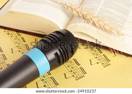 Close up of microphone and bible on a yellow music sheet
