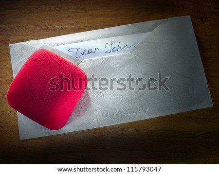 A red ring box over an envelope with the Dear John letter which is usually written to inform that a relationship is over, usually because the author has found another lover.