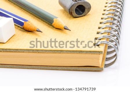 Two Wooden pencil, eraser and sharpener on recycle notebook on white background.