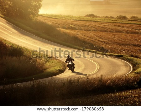 Motorcycle on countryside road at autumn evening.