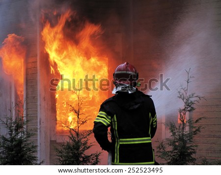 Firefighter sprays water to burning house.