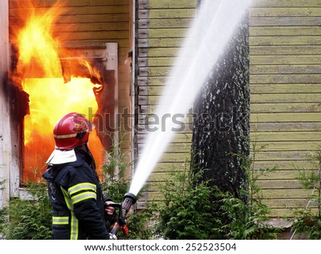 Firefighter sprays water to burning house.