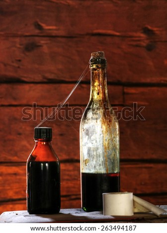 Old glass bottles tied together by cobweb on the table in old, abandoned farm house in Southern Finland.