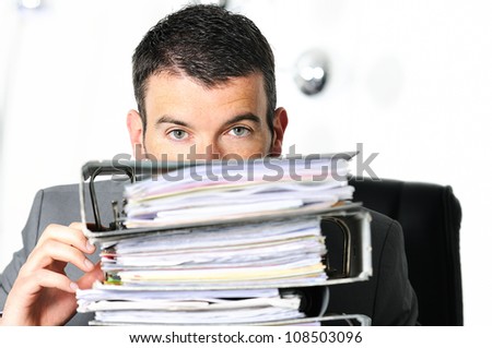 busy man hiding behind a stack of files