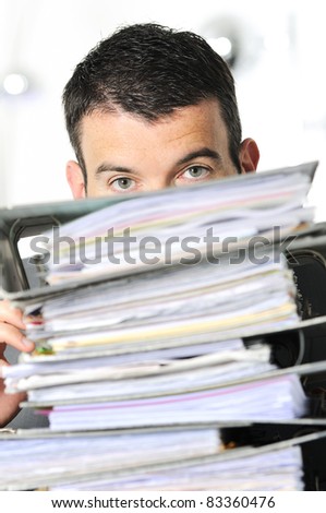 busy man hiding behind a stack of files