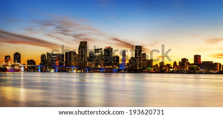 Miami city skyline panorama at dusk with urban skyscrapers over sea with reflection