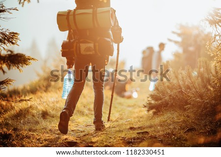 Traveller with a group hiking in the mountains at sunset.