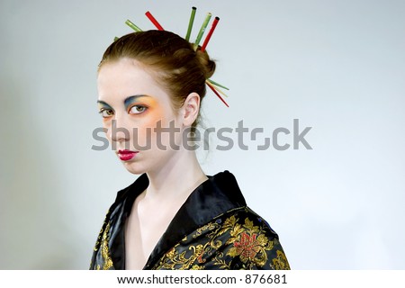 Attractive young woman wearing elaborate makeup with chopsticks in her hair bun