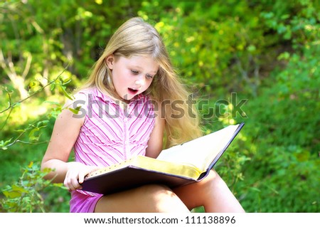 Child reading a book in the park