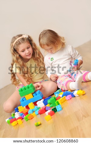 Kids playing with wooden blocks laying on the floor in their room