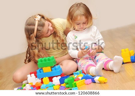 Kids playing with wooden blocks laying on the floor in their room