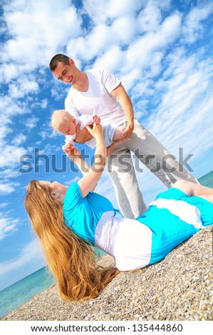Happy family of mother father and son playing on the beach and having fun
