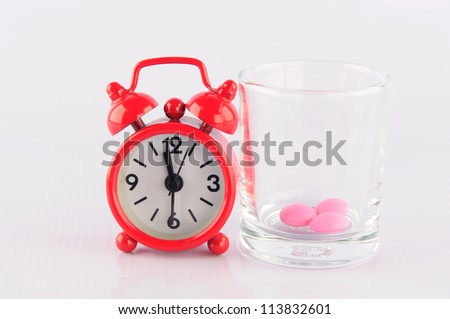 Red clock and medicine glass on white background show medicine time concept