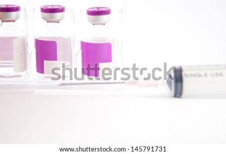 Purple label ampule in blister pack tray and disposable syringe on white background