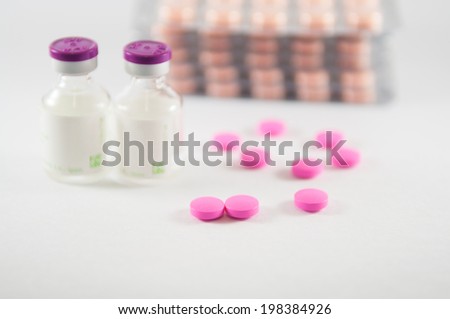 Pink tablet and injection vials on medicine background