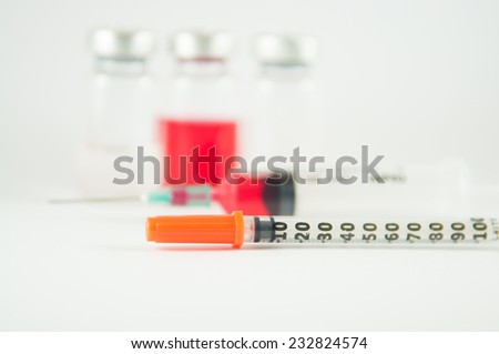 Disposable syringe and red liquid in injection vial