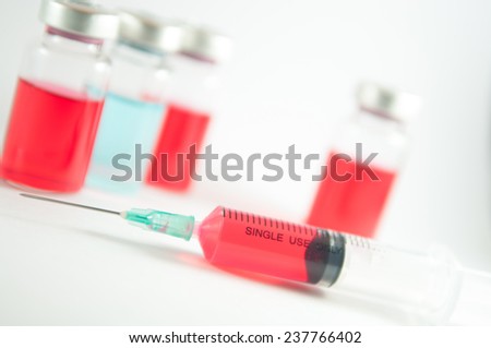 Red liquid in injection syringe and vials on red floor effect