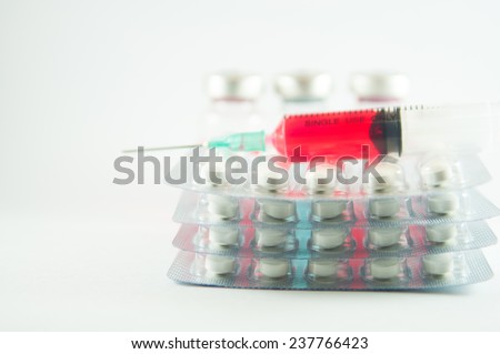 Red liquid in disposable syringe on blister pack and medication background