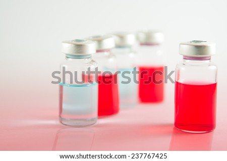 Red and blue liquid in injection vials on red floor effect