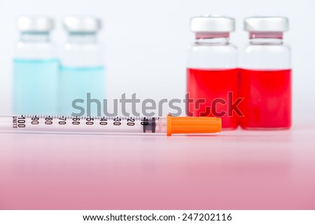 Disposable syringe and injection vials on red floor