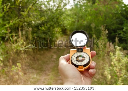 Compass in his hand tourist indicates the direction in the forest