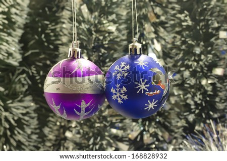 Two Christmas tree bulb hanging on a background of new year\'s tinsel