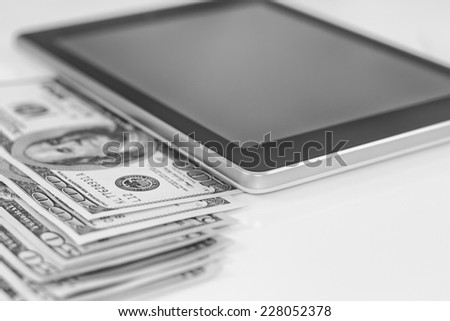 Tablet-PC and dollars on white background. Black and white photo