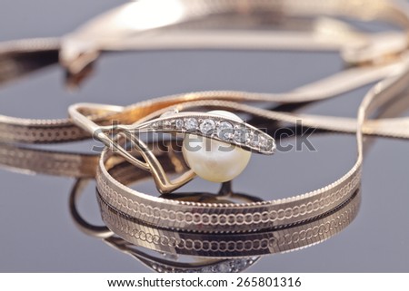 gold ring with pearl lies in the background of other gold jewelry